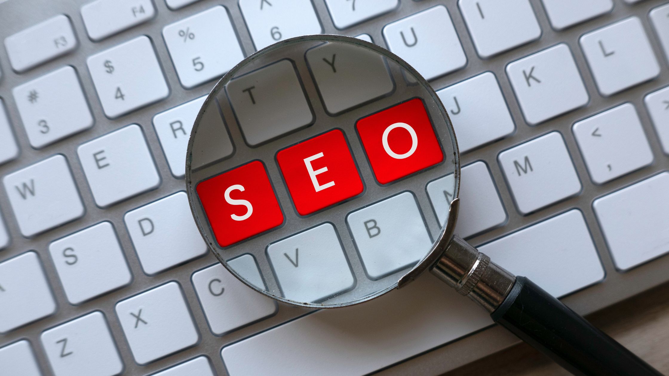 SEO in key letters on a keyboard with a magnifying glass spotlighting it. 