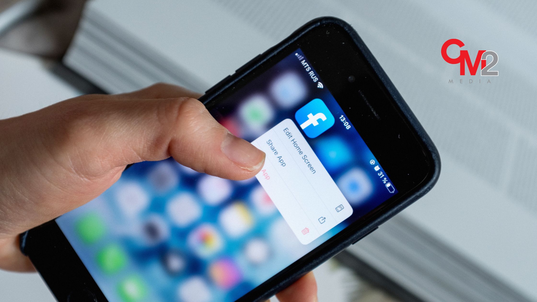 Close-up of a hand holding a phone and clicking the Facebook app - how to use Facebook for business growth.